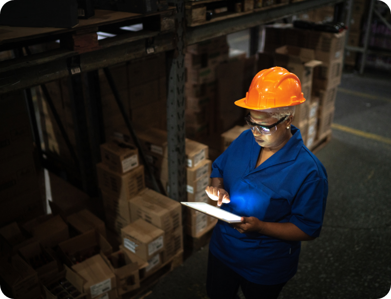 Woman in hardhat using tablet in warehouse