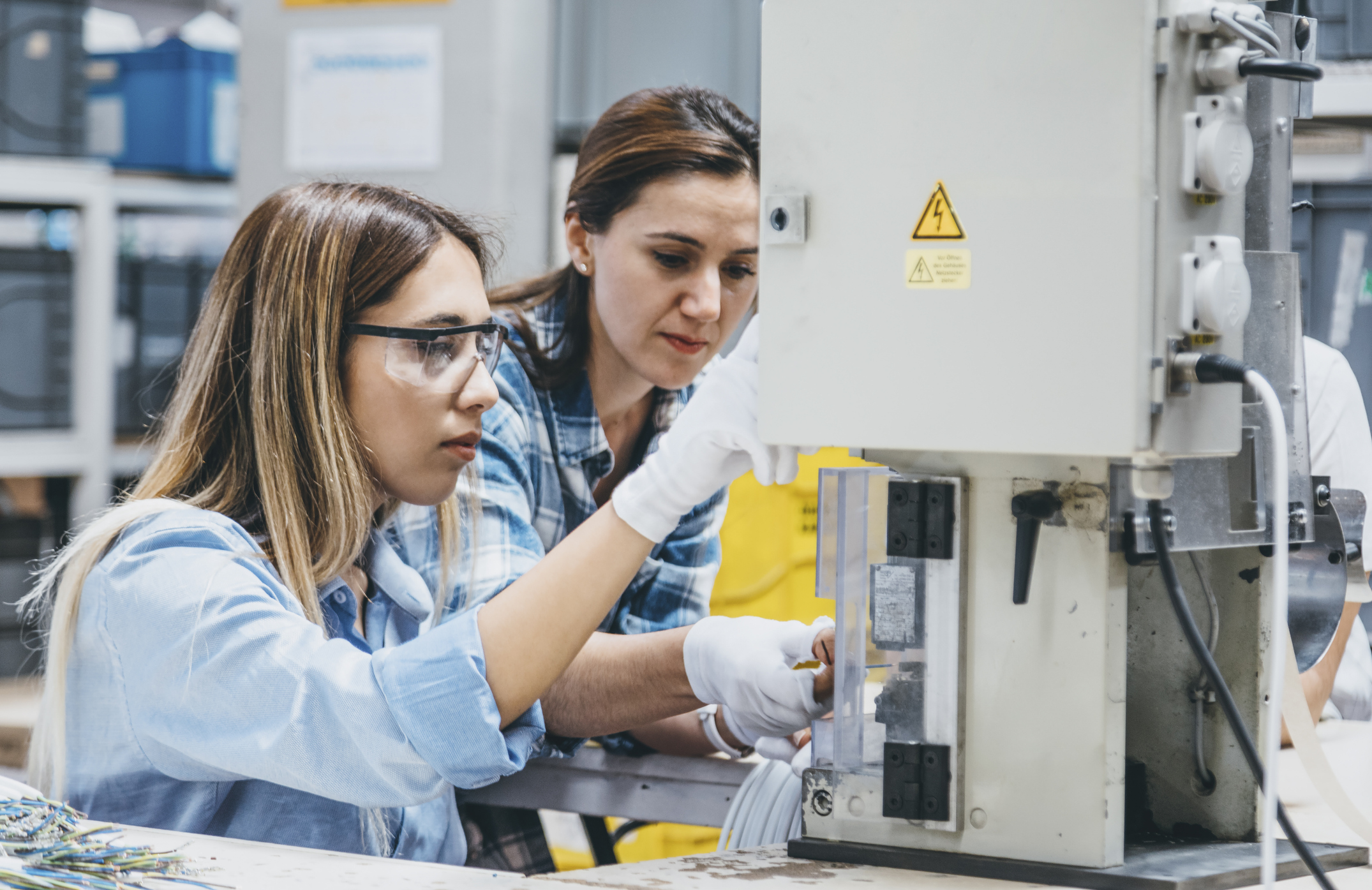 Female employees working with machine parts in a warehouse.