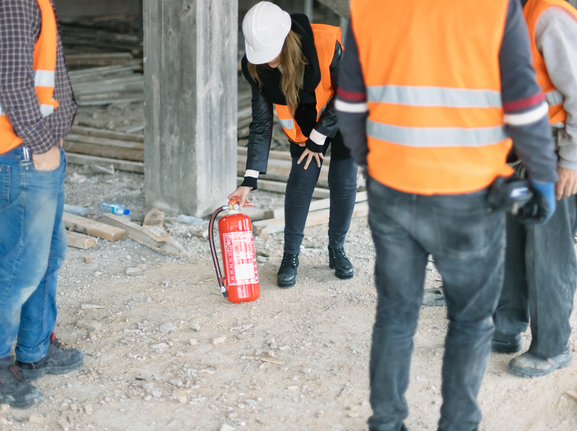 Female specialist explaining how to use fire extinguisher on construction site