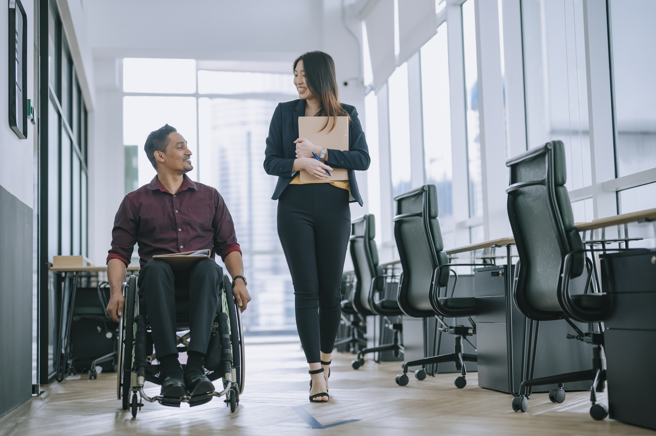 Male employee in wheelchair talking to female employee