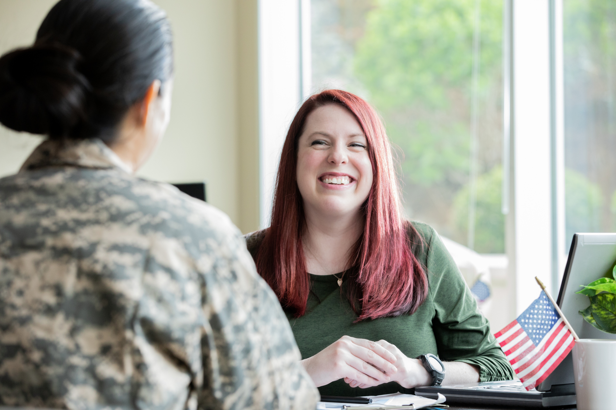 Woman speaking to military woman over desk