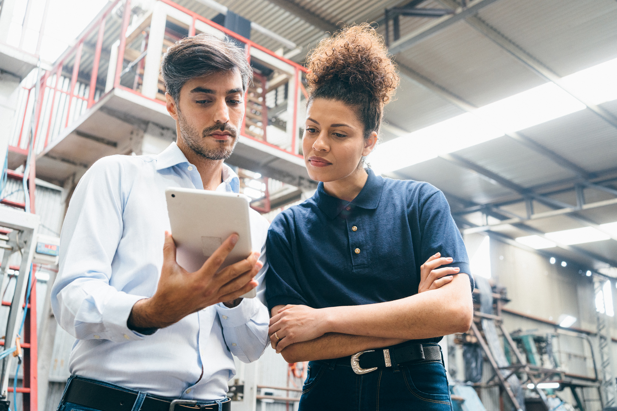 Male and female coworker discussing tablet in a warehouse