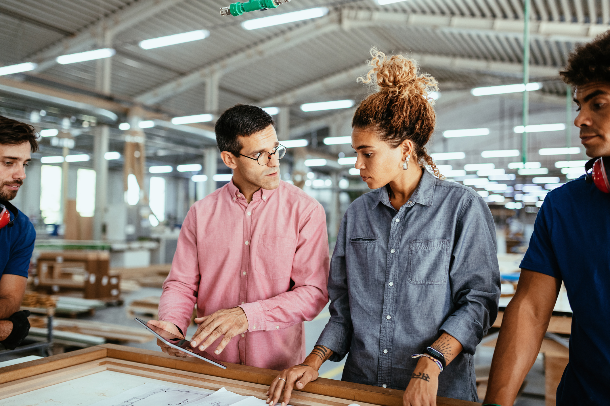 Employees discussing blueprints in a factory