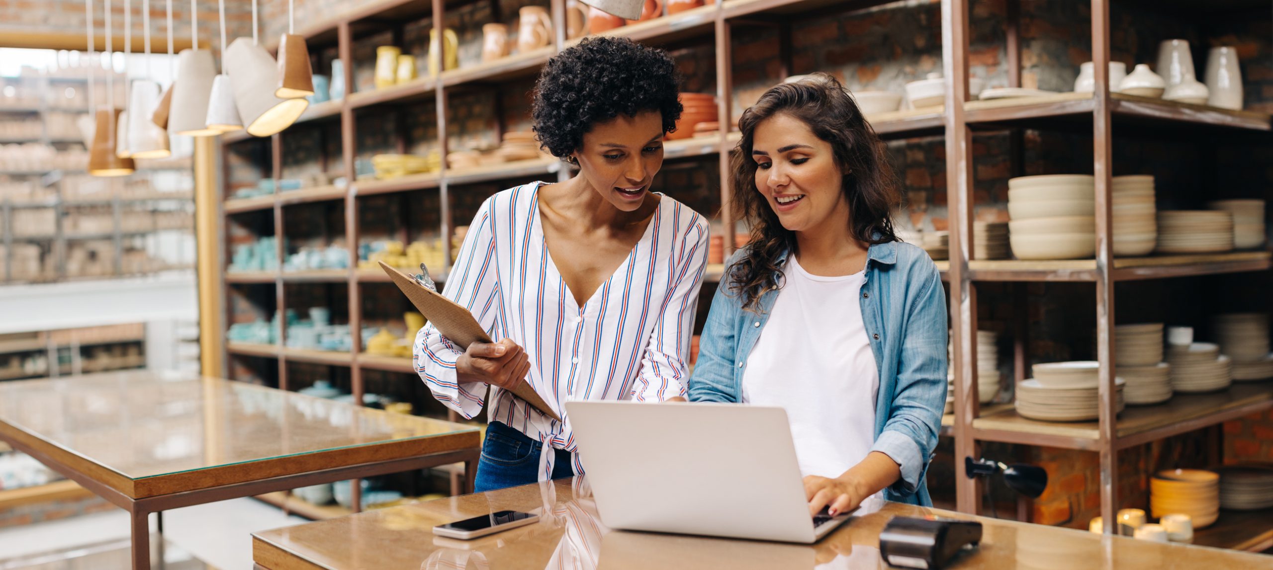 Two young shop owners using a laptop in their store