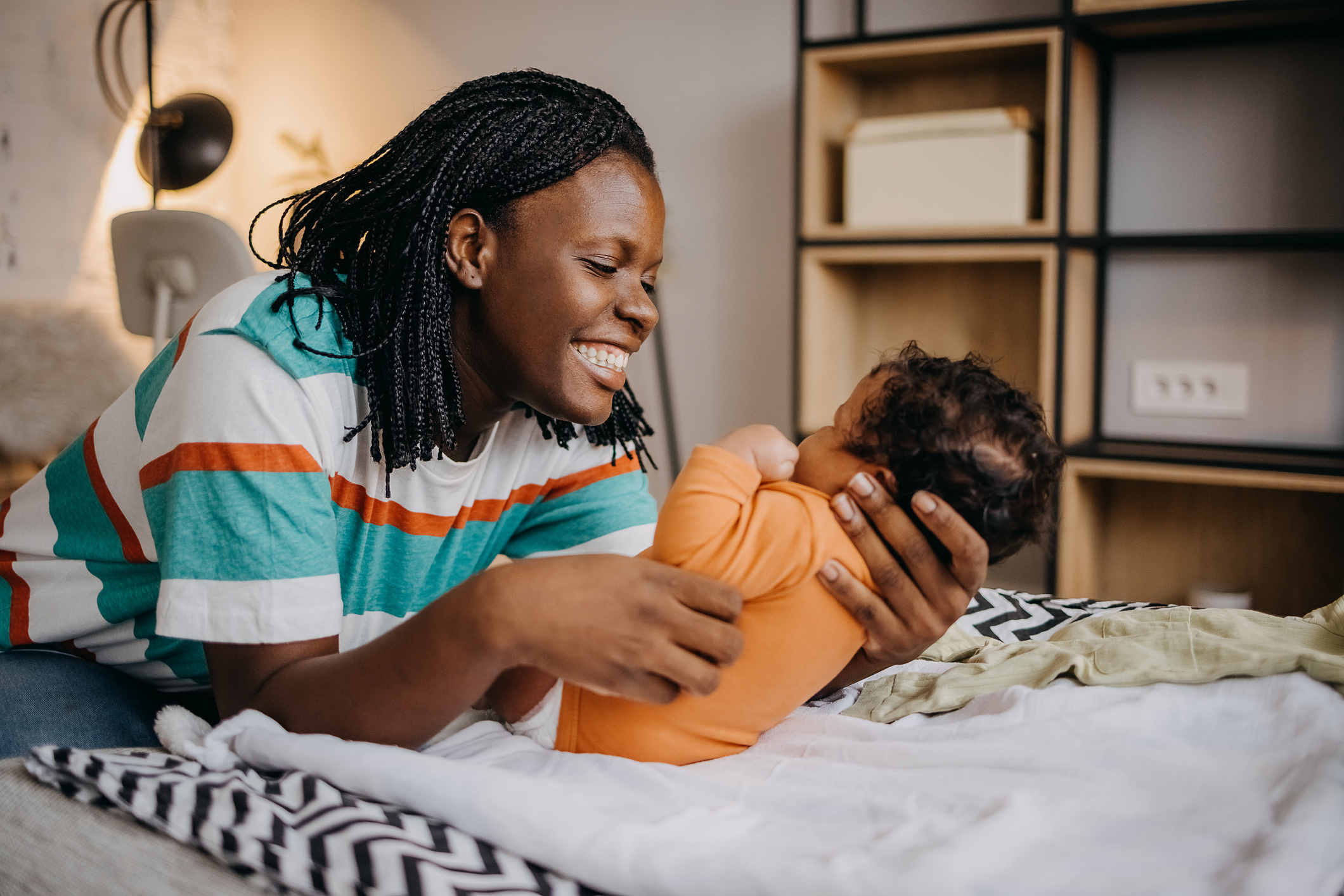 Young woman playing with her baby on the bed at home