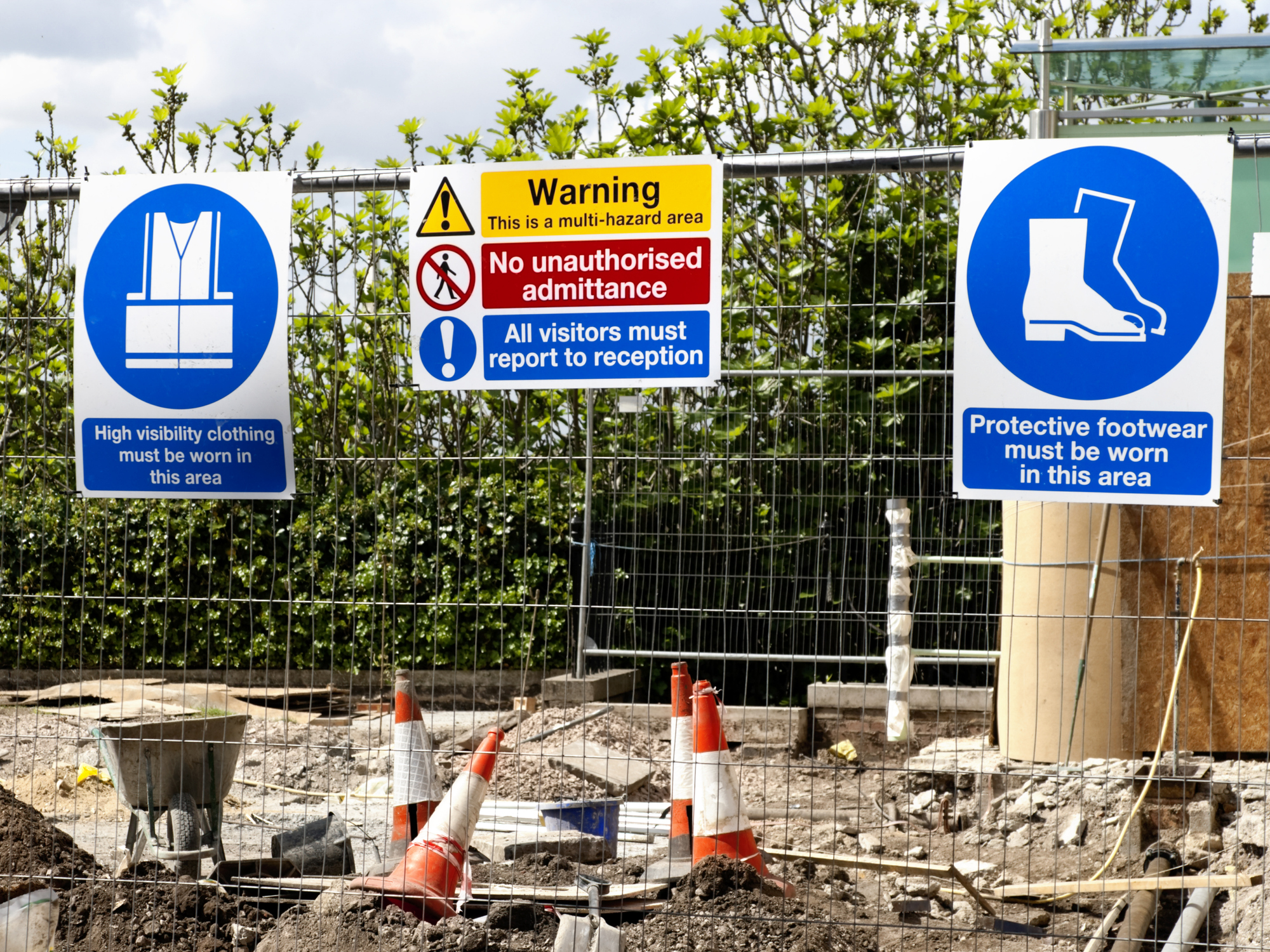 Safety signs on a construction site fence.
